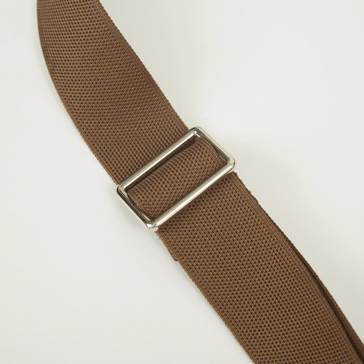 Brown adjustable knitted shoulder strap detail featuring woven texture, metal buckle and soft recycled polyester yarn construction.