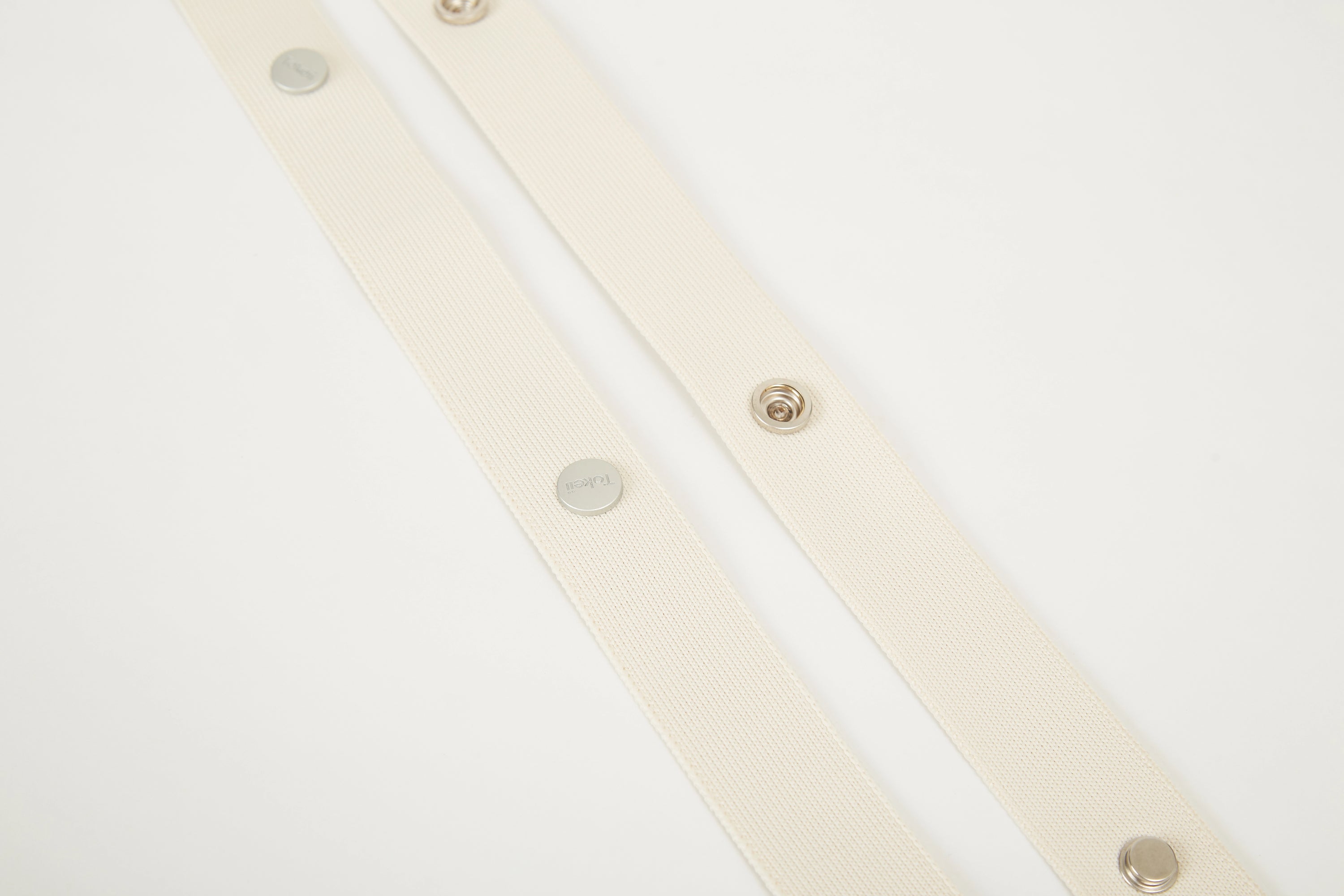 Beige Colorway Strap detail with Tokeii logo hardware and snap buttons.