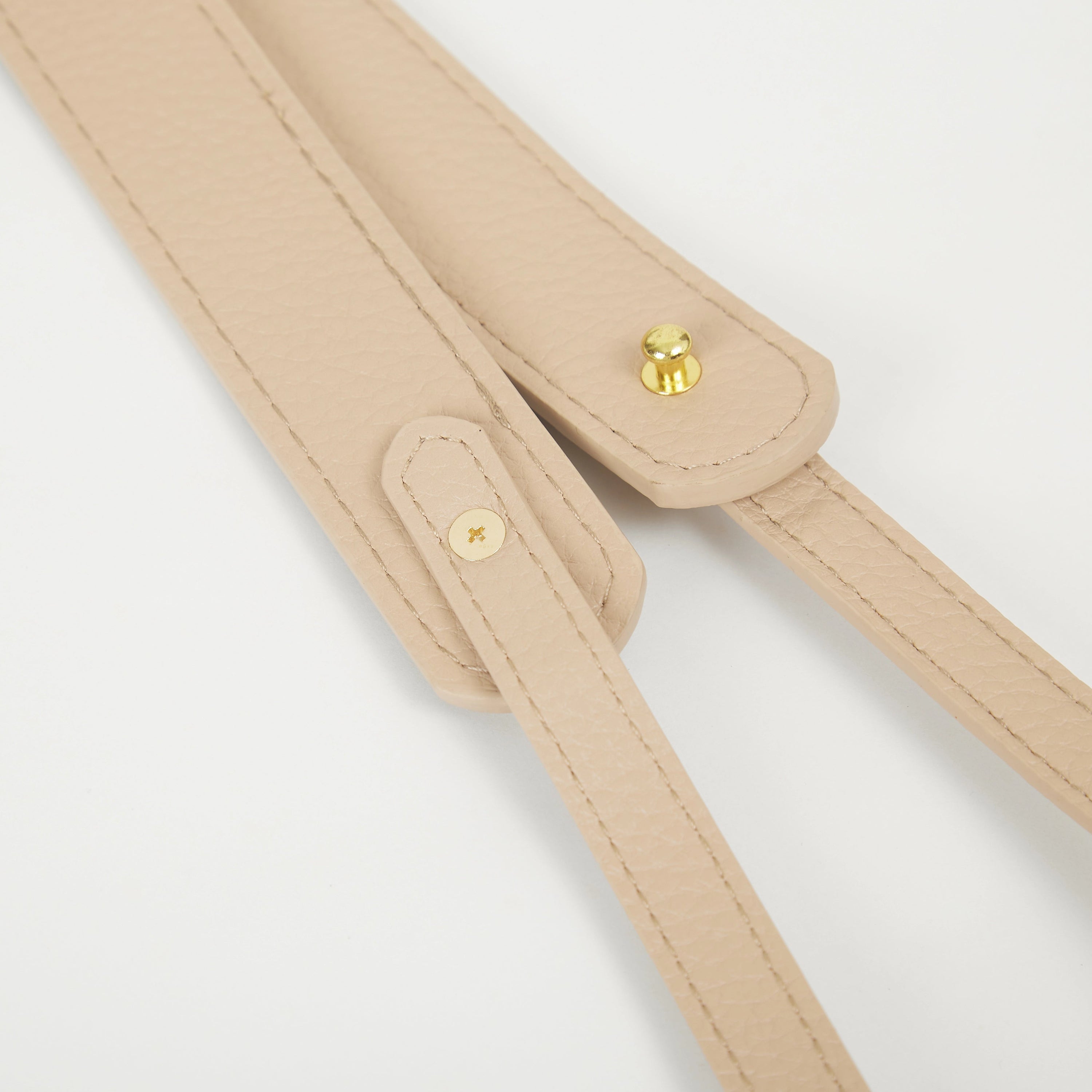 Close-up of beige faux leather Colorway Strap showing stitched edges and snap button details.