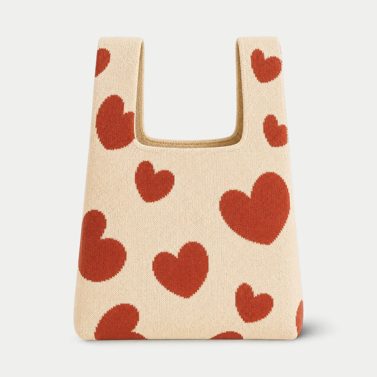 Beige knit tote bag with brick red heart pattern, featuring a soft textured design and everyday silhouette.