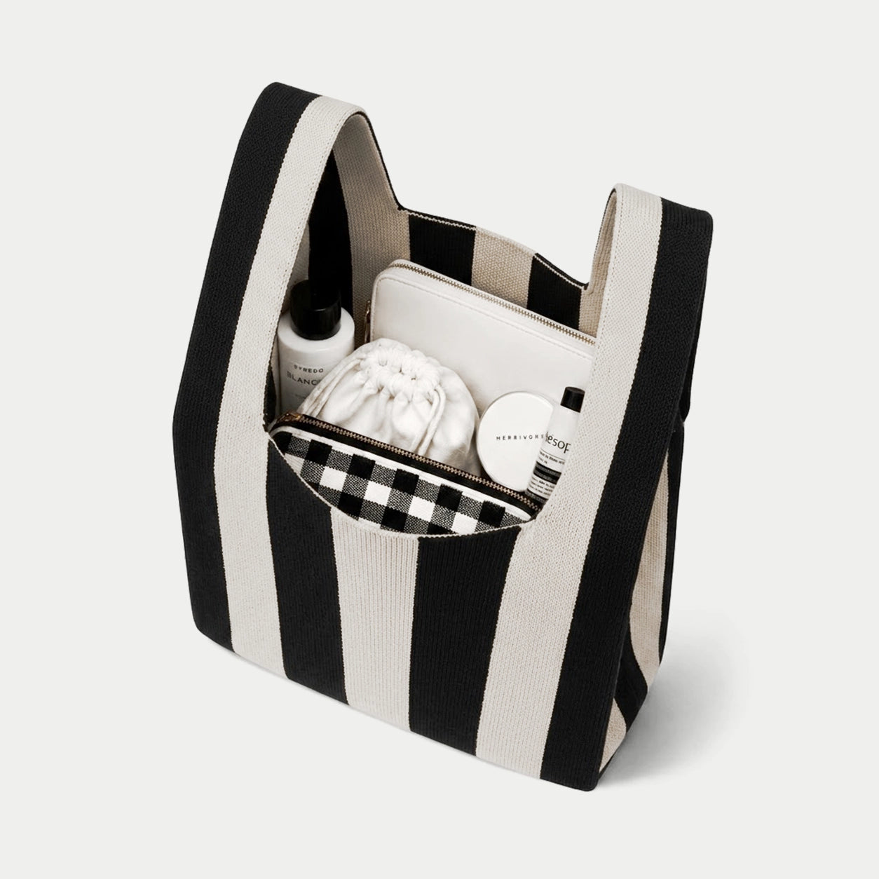 Black and white  vertical stripe knitted tote bag showing the spacious interior and capacity for carrying everyday essentials with its soft knitted construction.