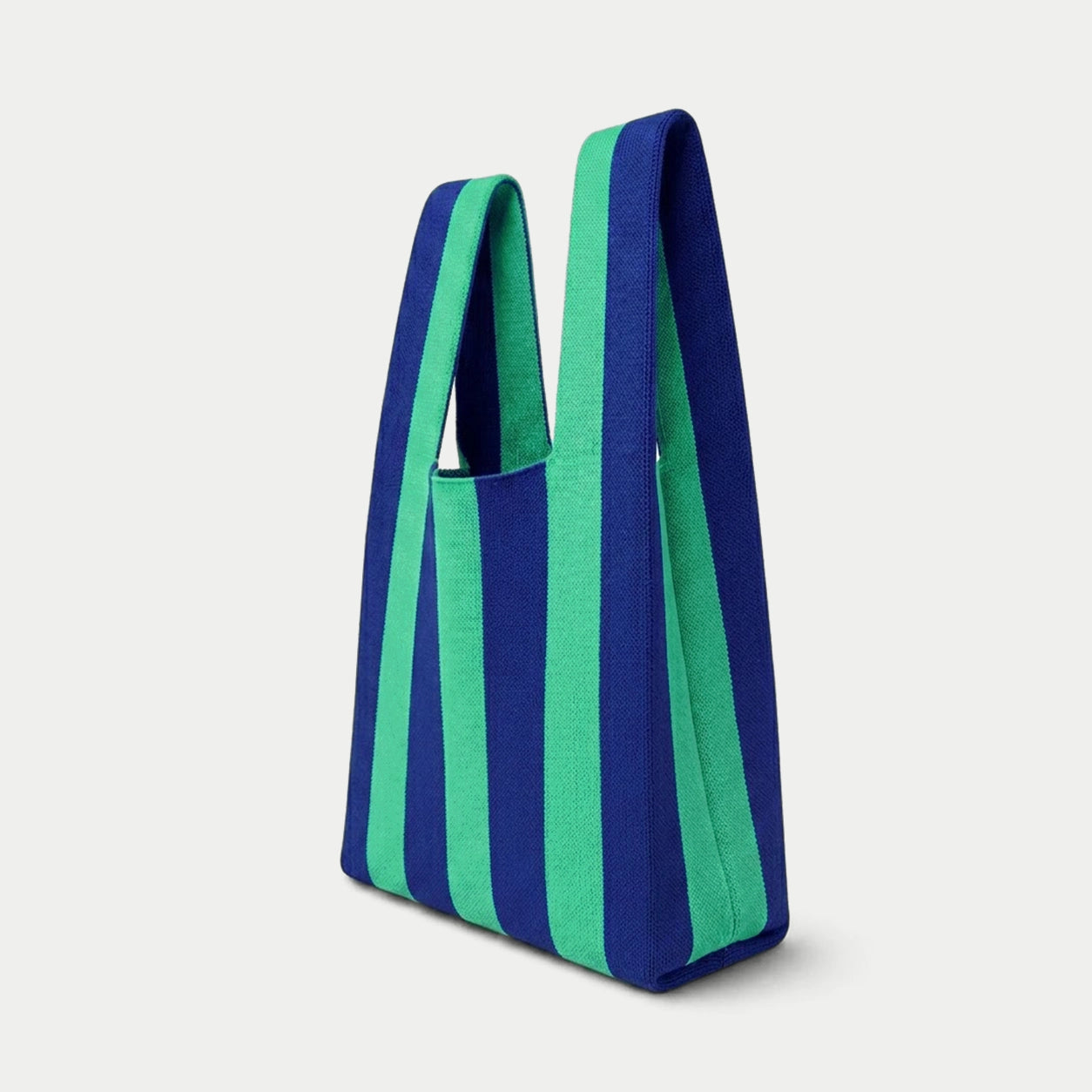 Side view of blue and green vertical stripe knitted tote bag showing the structured silhouette, handle design and textured knit construction.