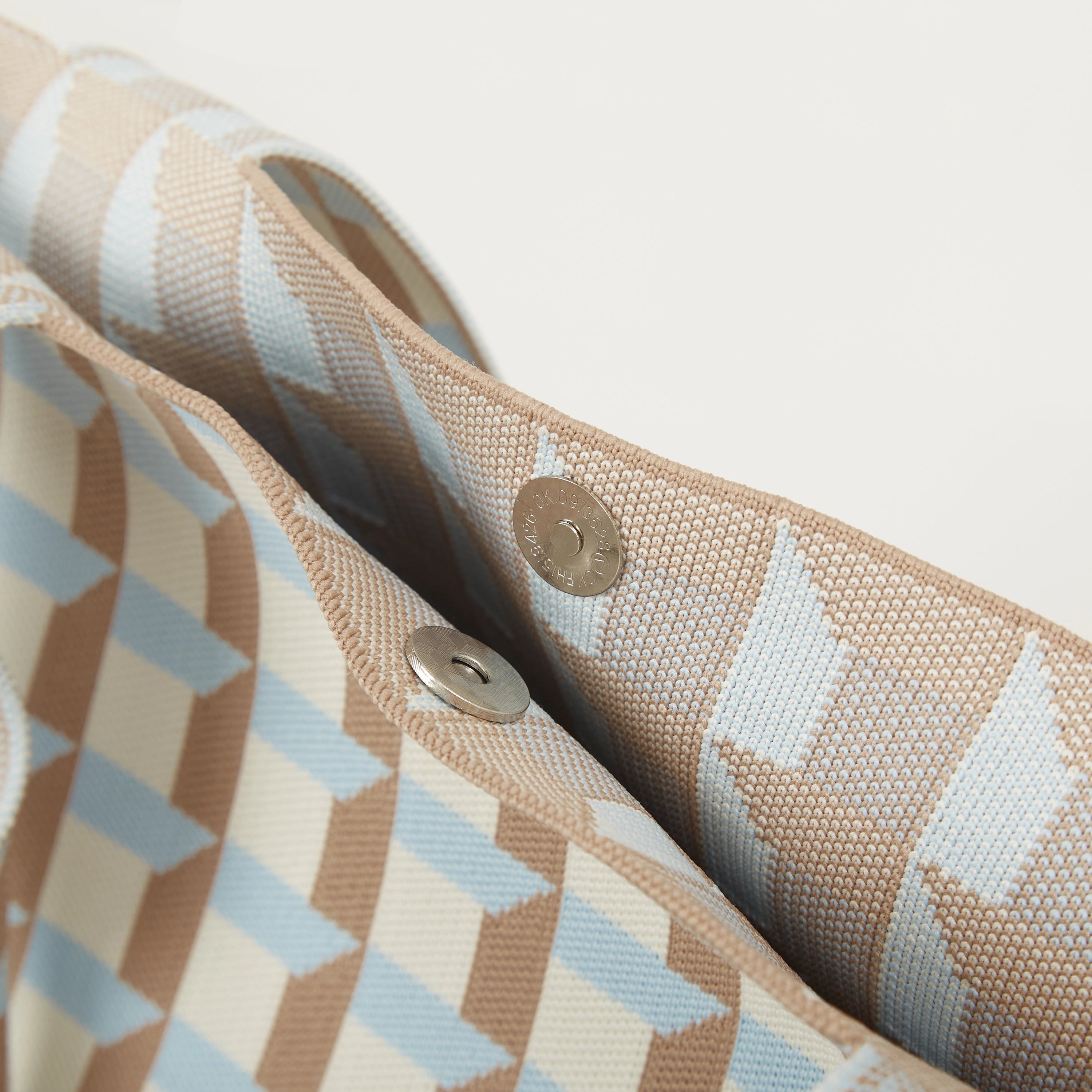 Knitted tote bag interior with geometric check pattern and snap button closure detail.
