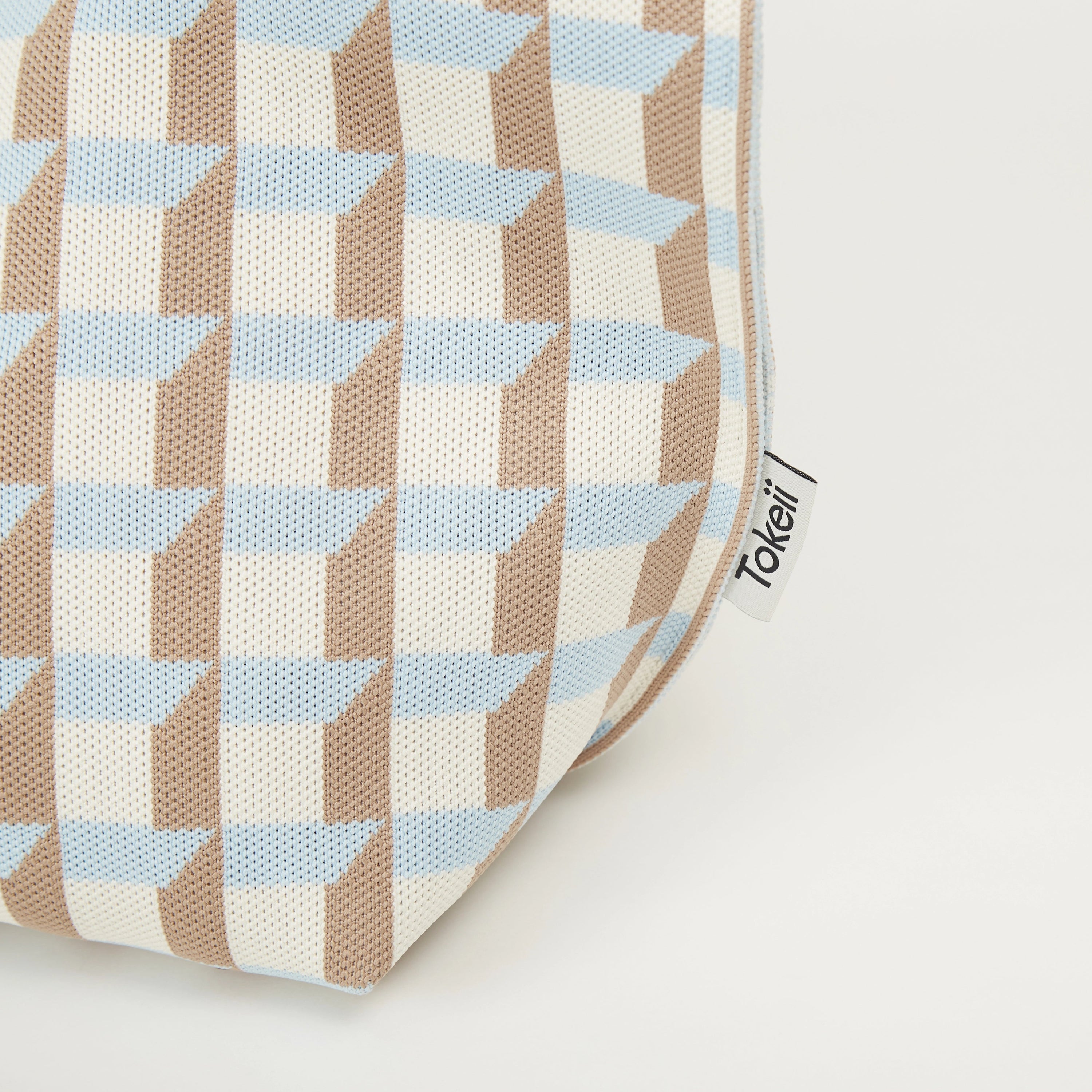 Side view detail of geometric check knitted tote bag showing gusseted shape and woven texture.