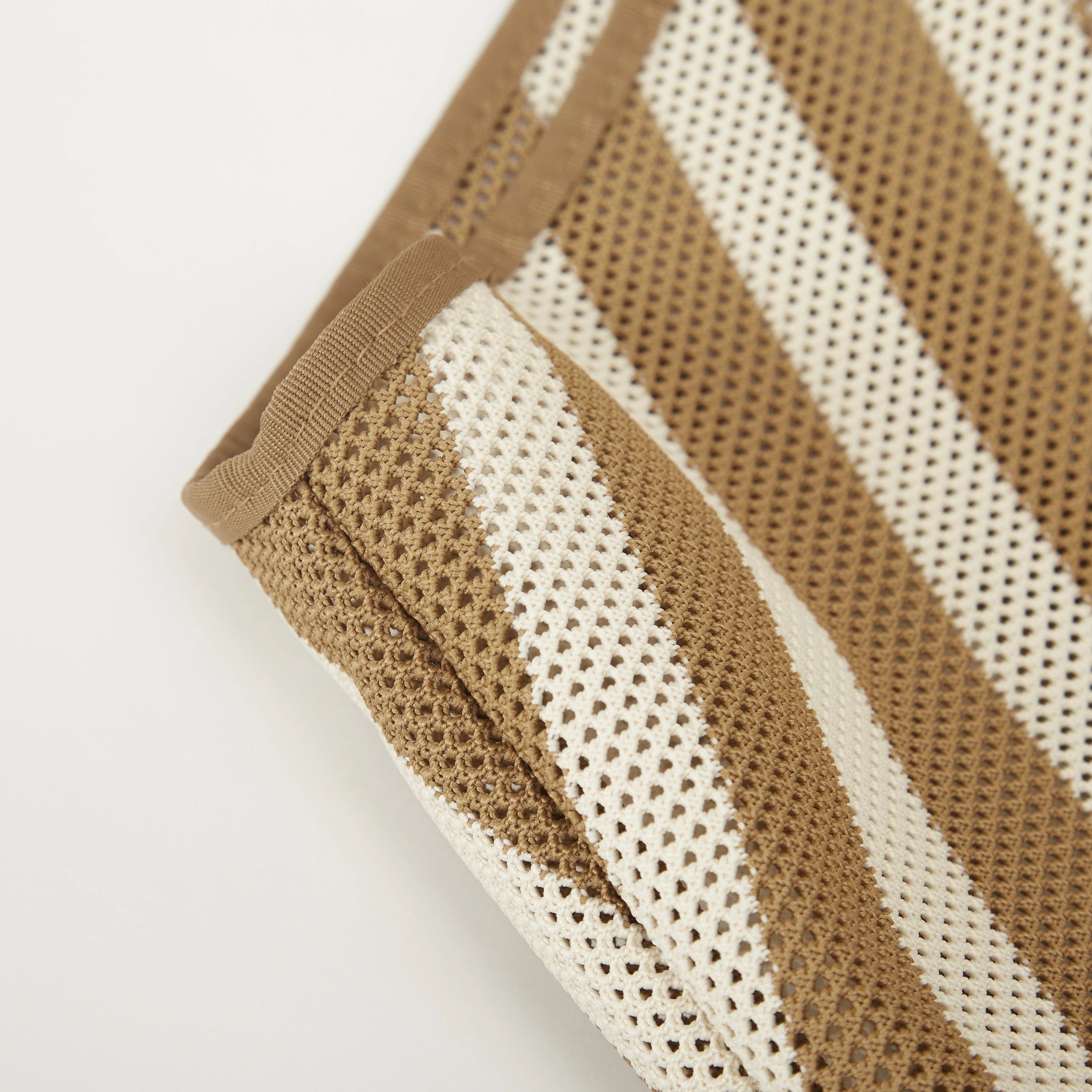 ide detail of camel beige striped mesh knit tote bag highlighting the gusseted shape and lightweight knitted construction.