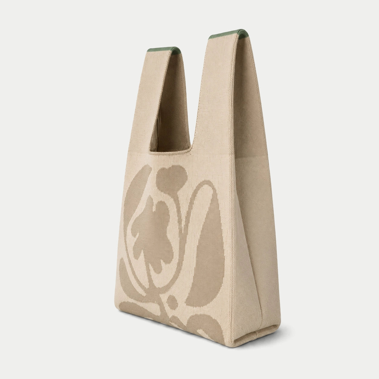 Side view of grey oversized flower  knitted tote bag showing the structured silhouette, handle design and textured knit construction.