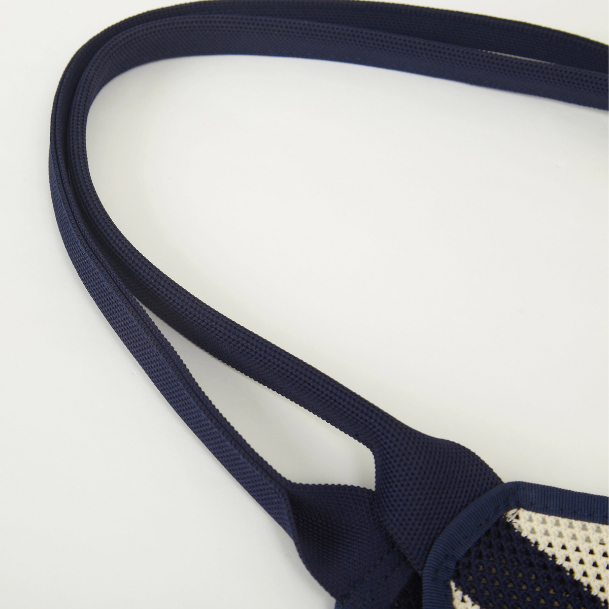 Close-up view of navy and beige striped mesh knit tote bag showing the soft knit texture and handle construction.