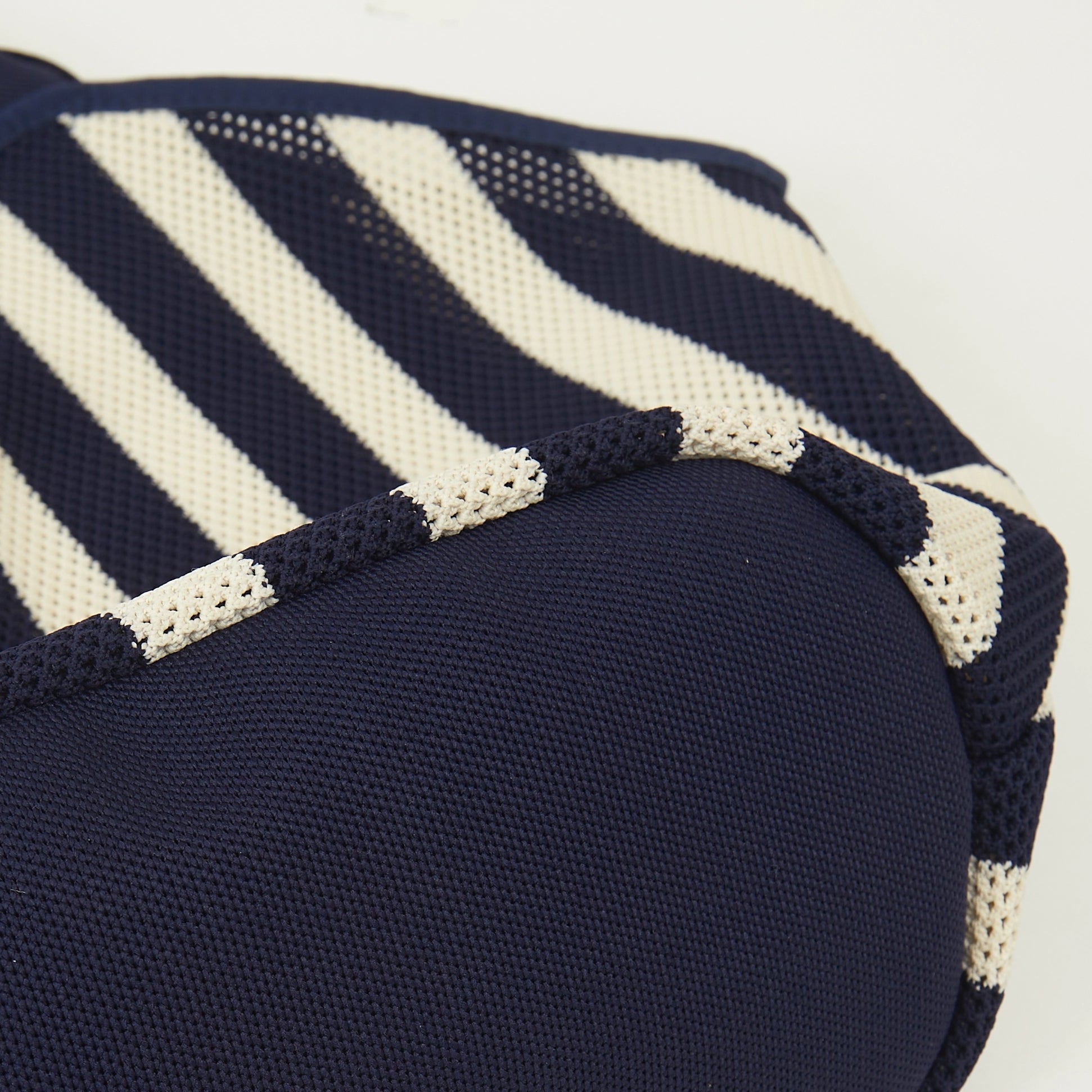 Bottom detail of navy and beige striped mesh knit tote bag showing the soft knit base and natural folds created by the relaxed material.