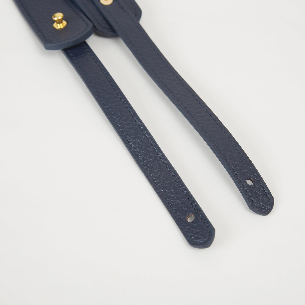Close-up of navy faux leather Colorway Strap showing stitched edges and snap button details.