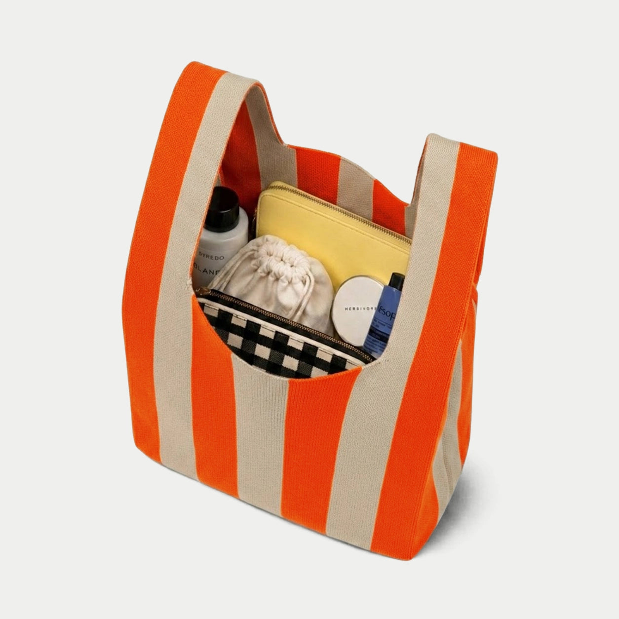 Orange vertical stripe knitted tote bag showing the spacious interior and capacity for carrying everyday essentials with its soft knitted construction.