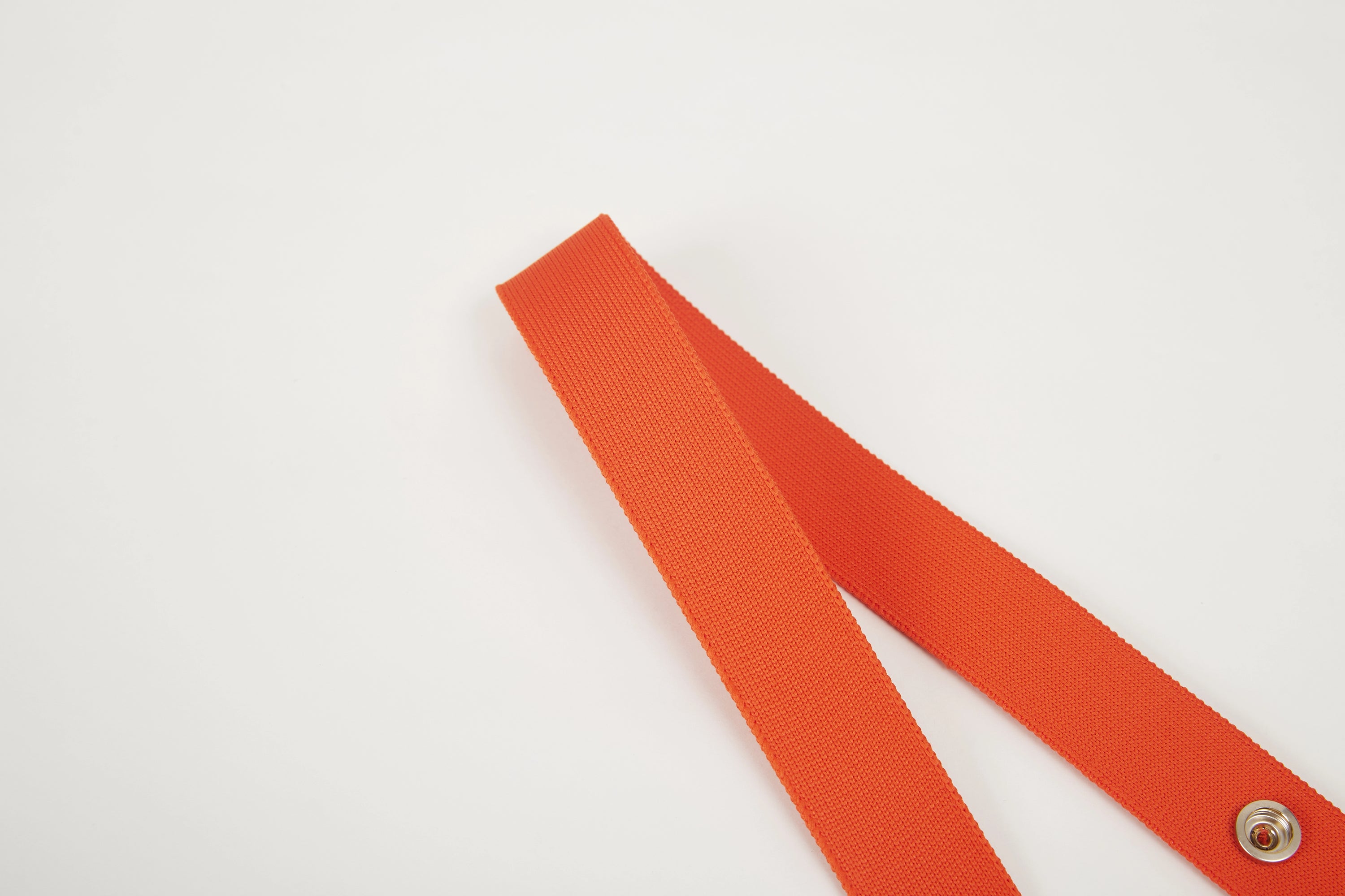 Close-up of orange Colorway Strap showing woven texture and metal snap details.