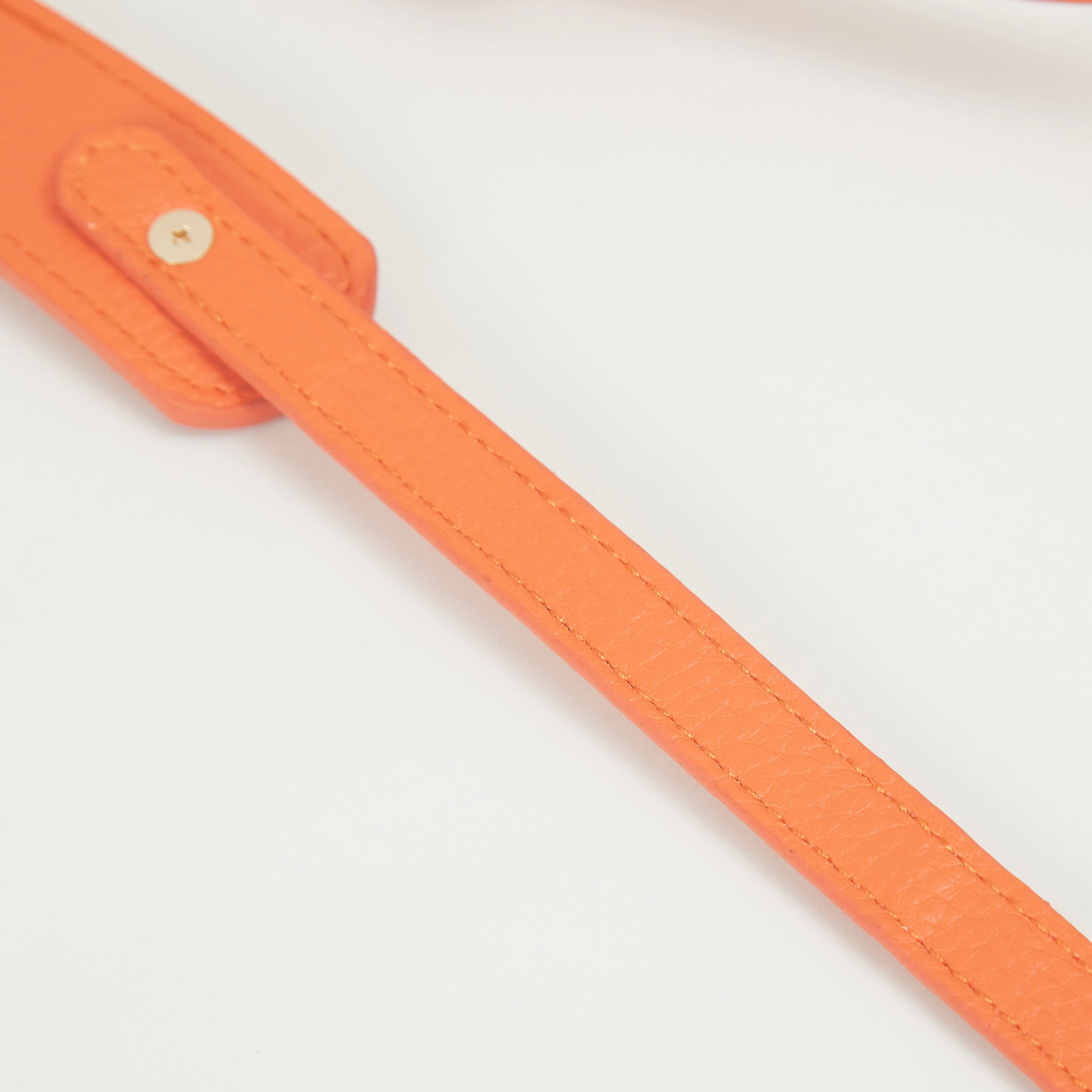 Close-up of orange faux leather Colorway Strap showing stitched edges and snap button details.