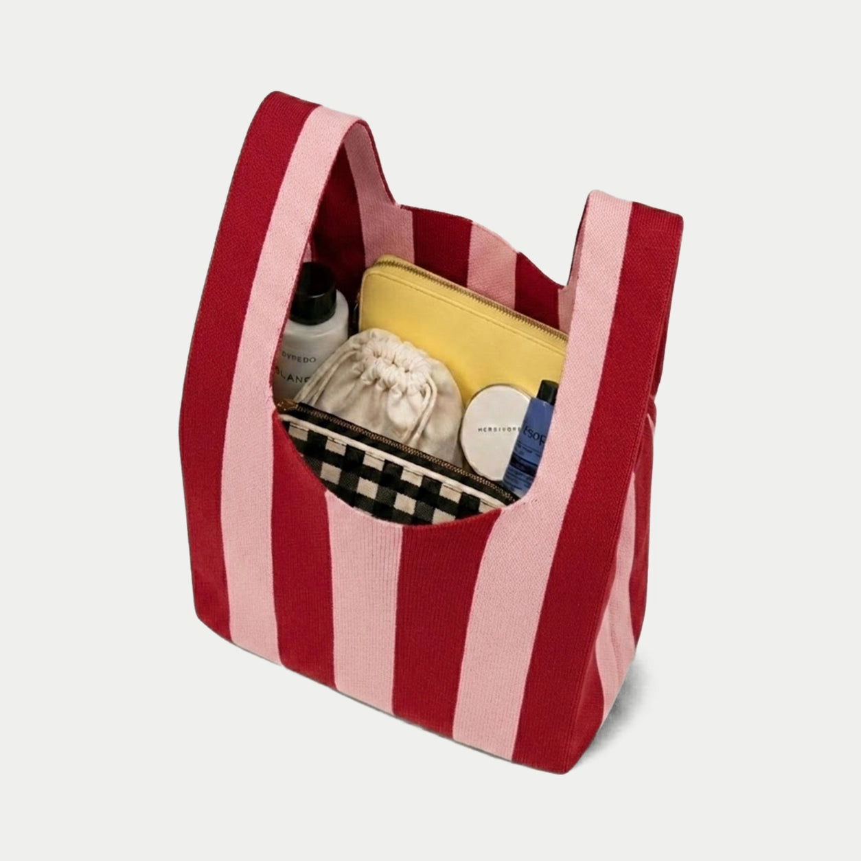 Pink and red vertical stripe knitted tote bag showing the spacious interior and capacity for carrying everyday essentials with its soft knitted construction.