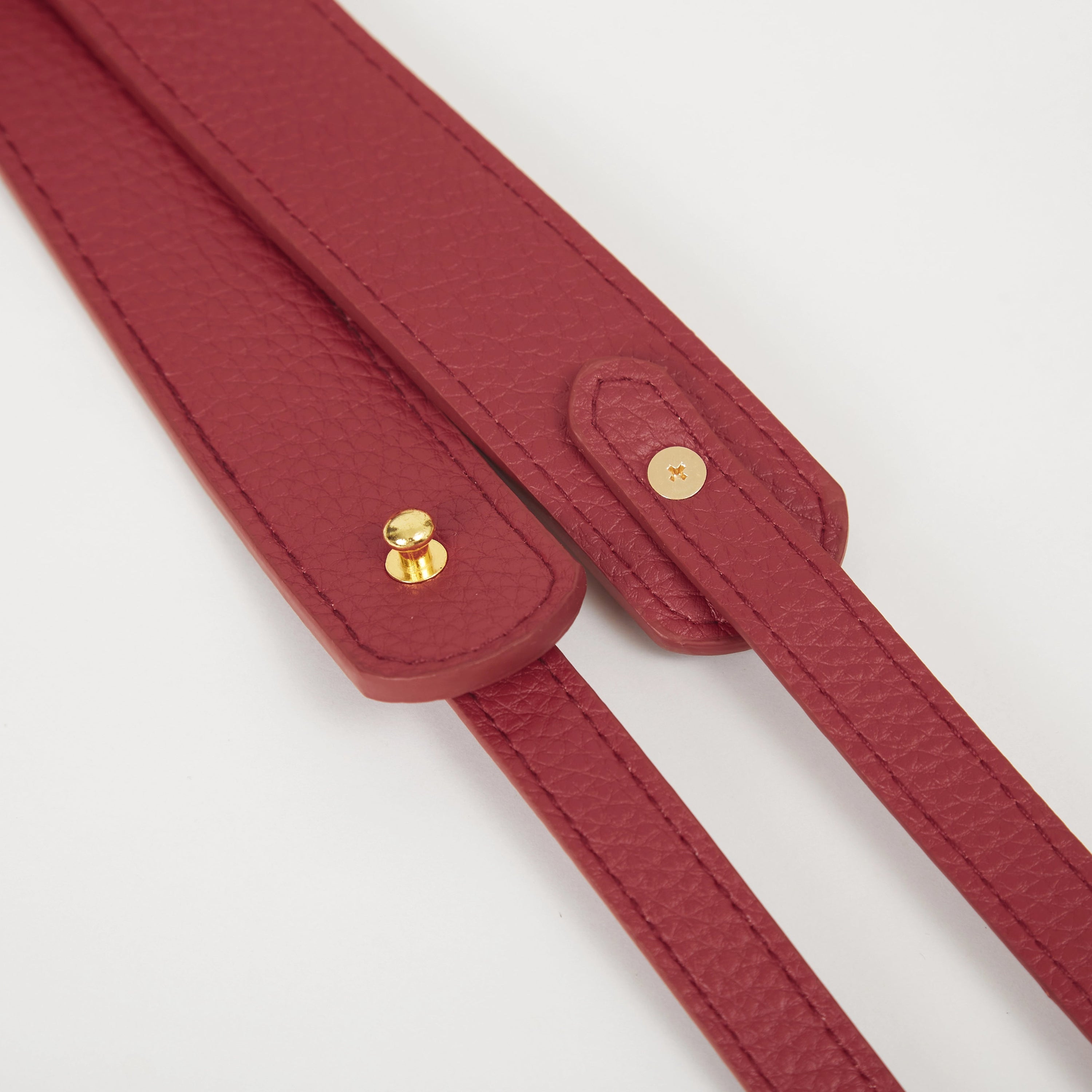 Close-up of red faux leather Colorway Strap showing stitched edges and snap button details.