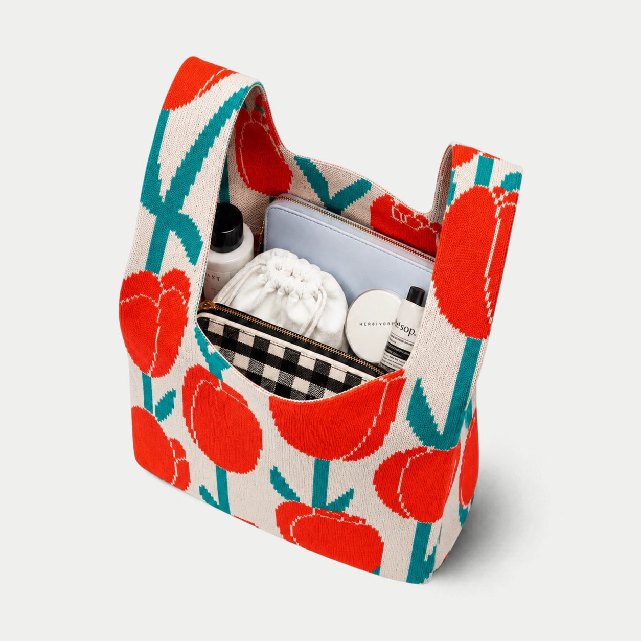 Top view of red, cream and teal tulip pattern knitted tote bag showing its practical capacity for carrying cosmetics, pouches and everyday essentials.