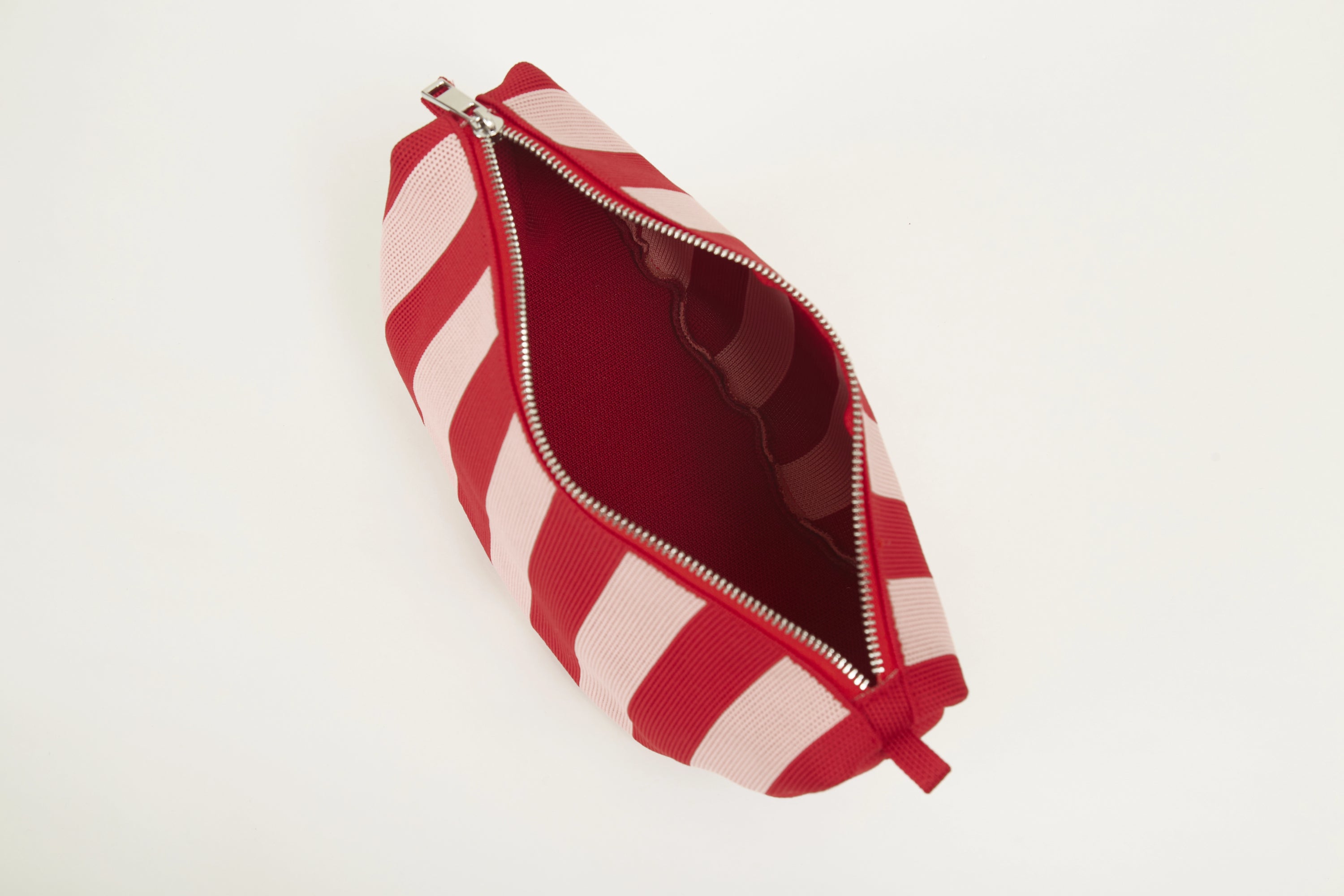 Red vertical stripe knitted half moon crossbody bag showing the spacious compartment, pure knitted construction and soft recycled polyester yarn texture.