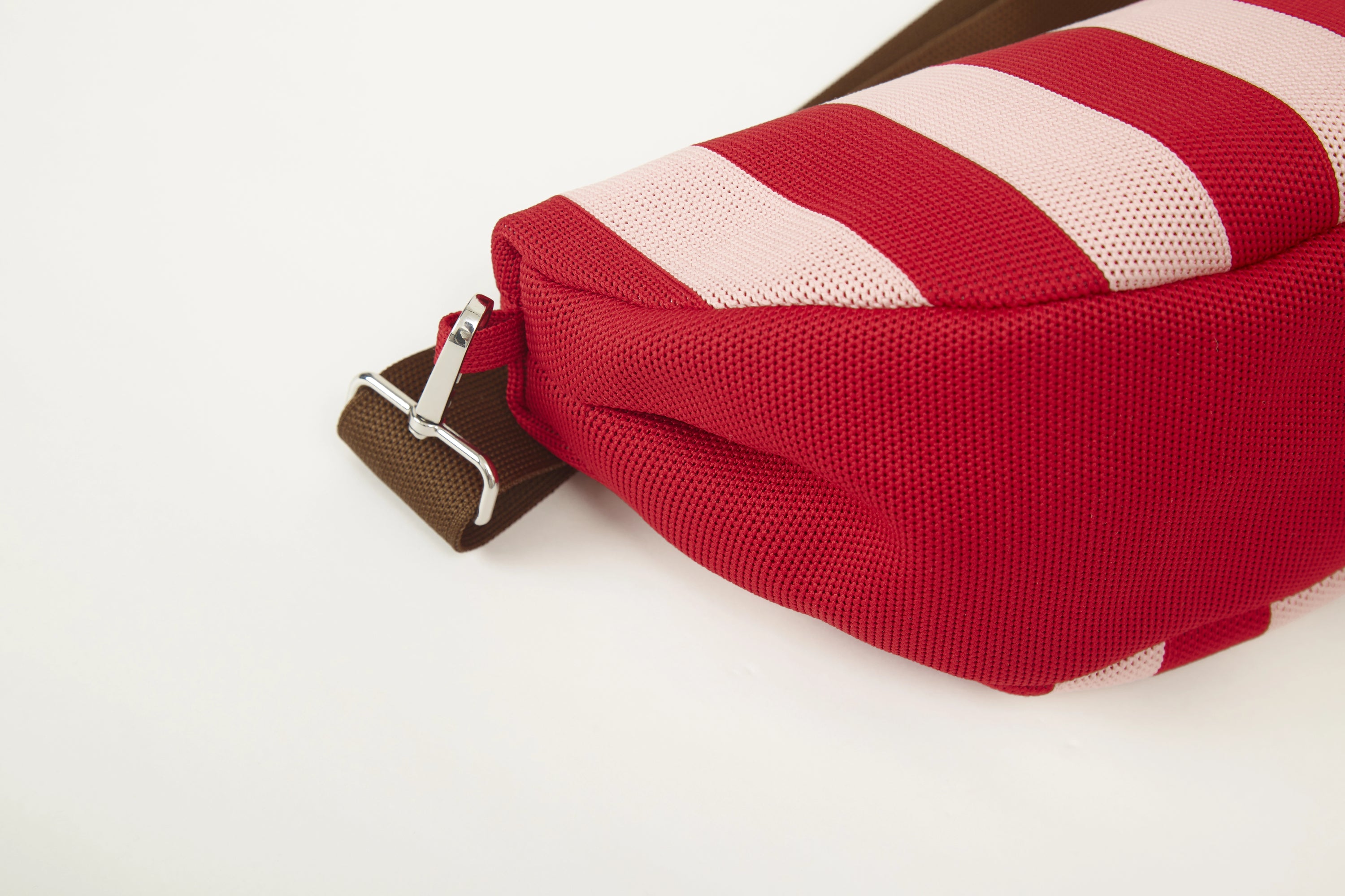 Red vertical stripe knitted half moon crossbody bag side detail showing the curved silhouette, structured shape and woven knit texture.