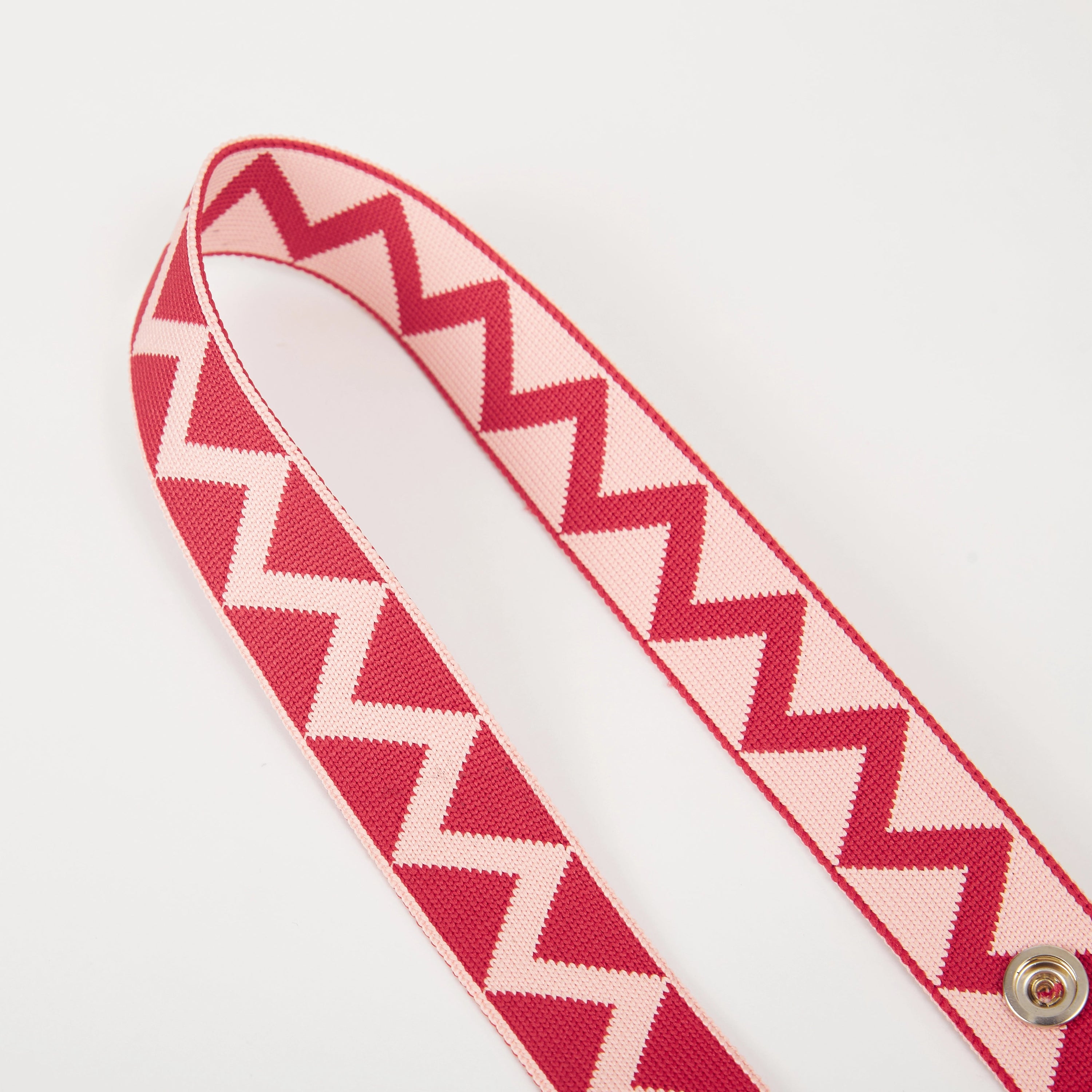 Close-up of red zigzag pattern bag strap showing woven texture, snap buttons, and detailed pattern.