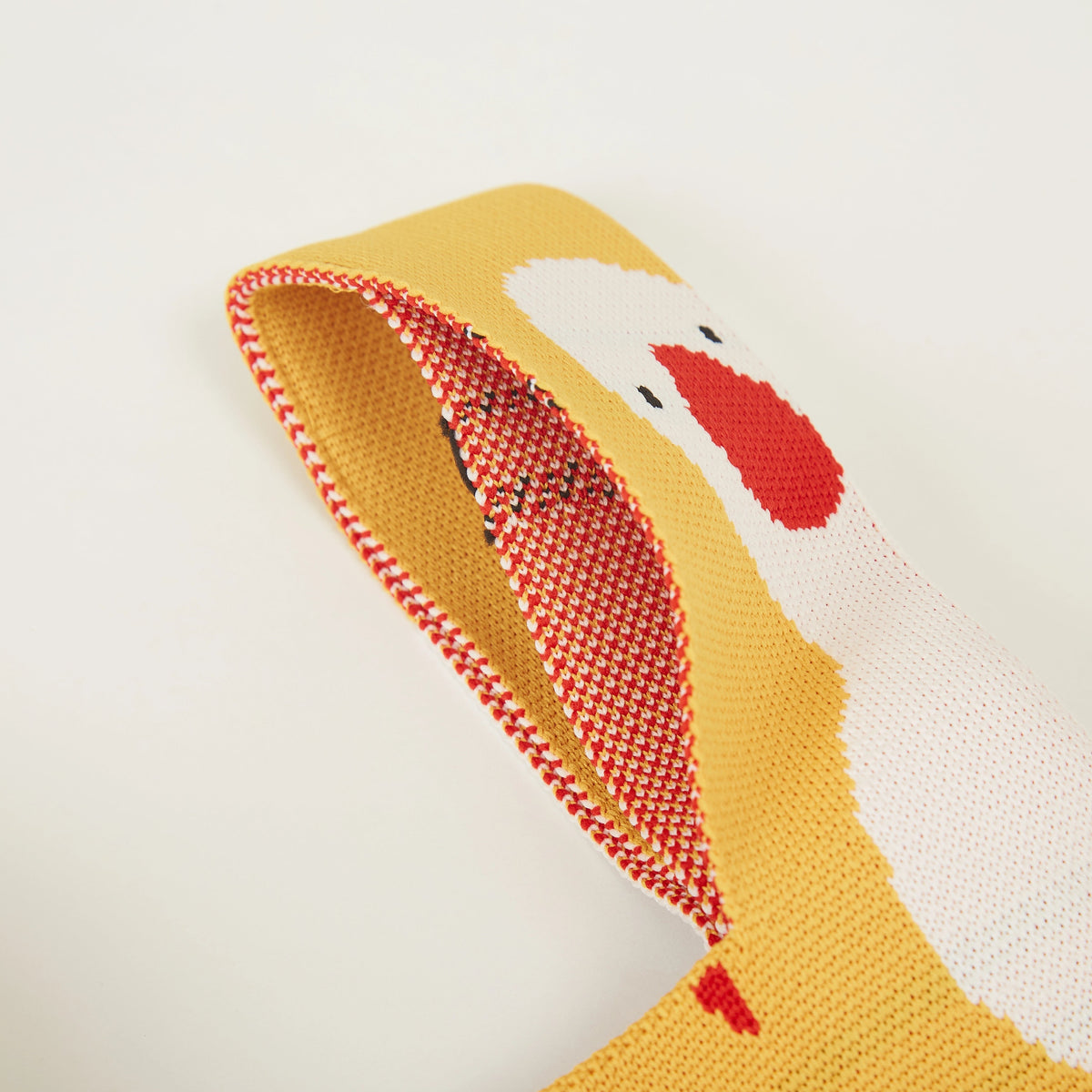 Detail view of yellow duck pattern knit tote bag edge and handle construction.