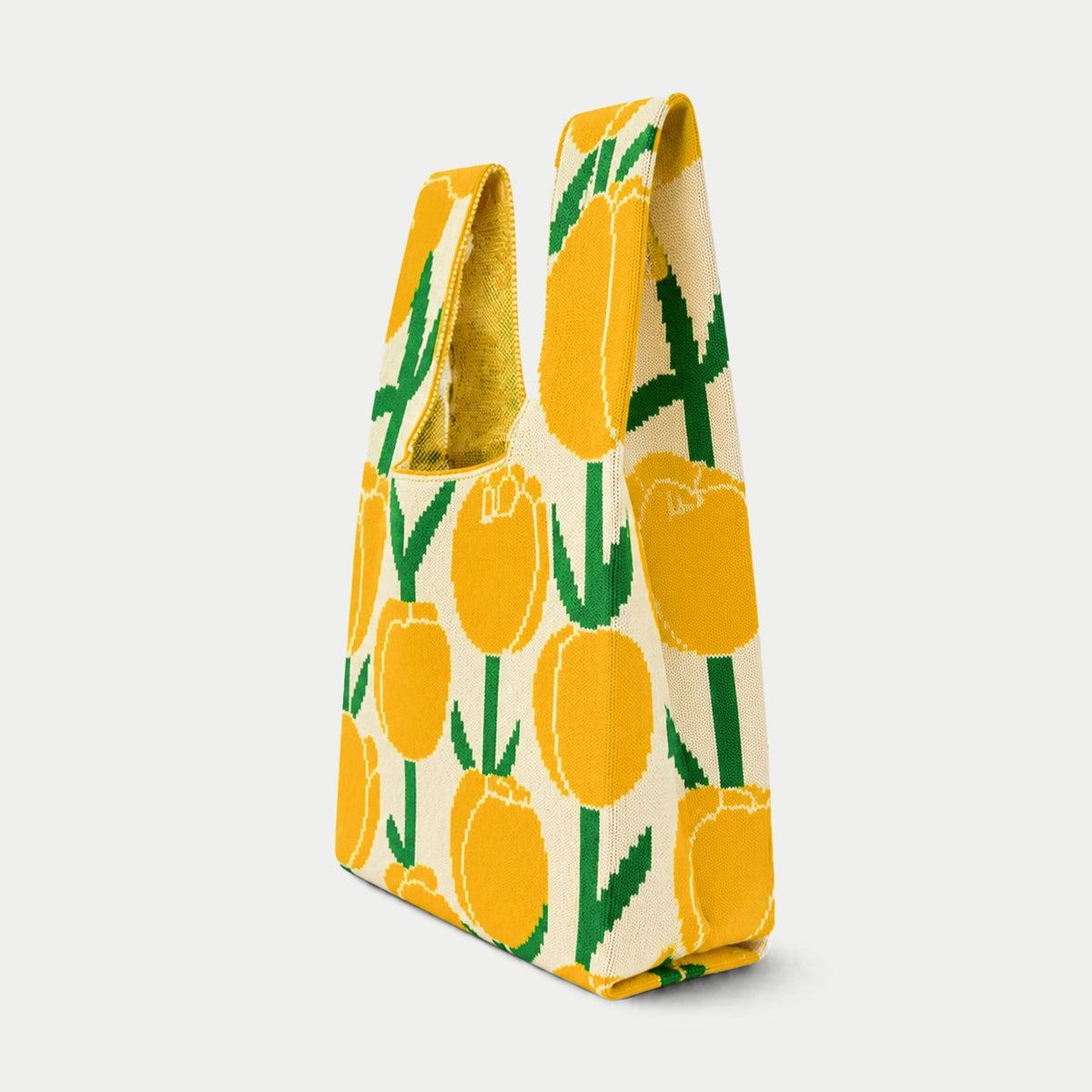 Side view of yellow, cream and green tulip pattern knitted tote bag showing the bag profile, side depth and textured knit construction.