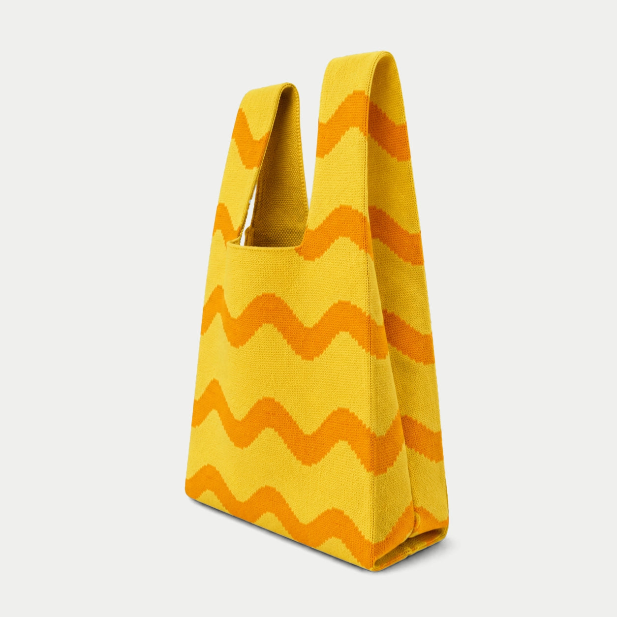 Side view of the yellow Wave Pattern Knit Tote Bag showing orange wavy stripes, integrated handles and side gusset.
