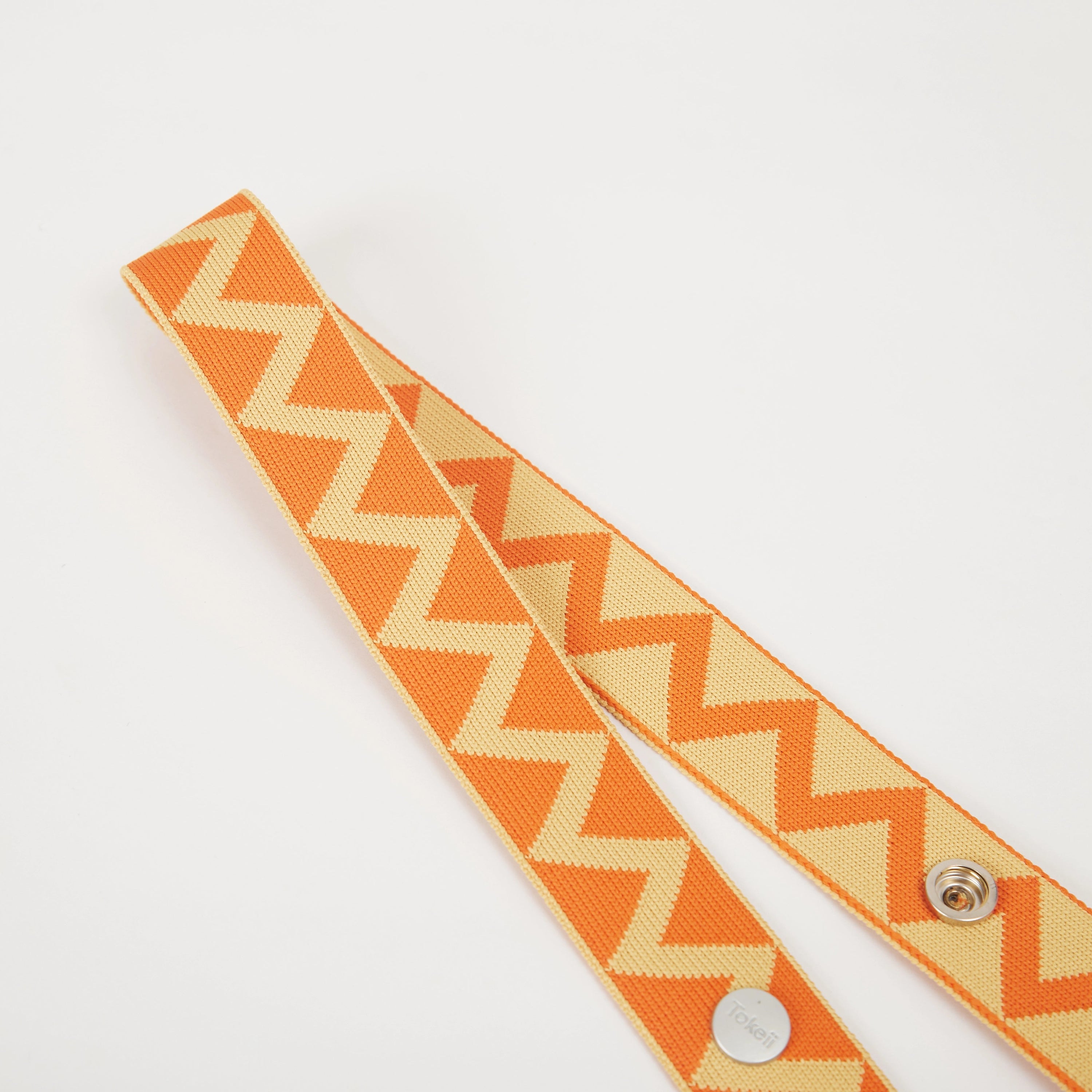 Close-up of yellow zigzag pattern bag strap showing woven texture, snap buttons, and patterned surface.
