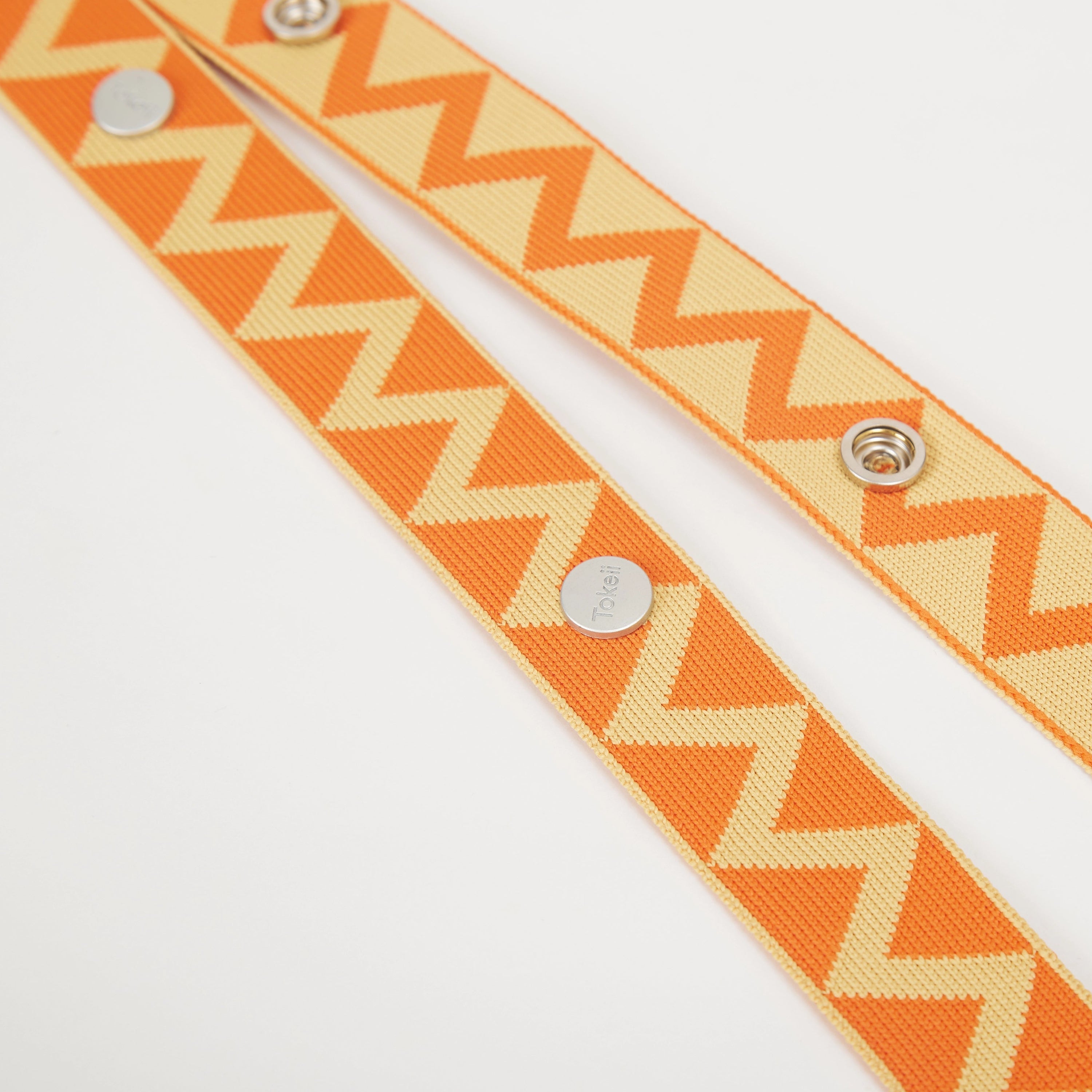 Detail view of yellow patterned bag strap highlighting the repeating zigzag design and fastening details.